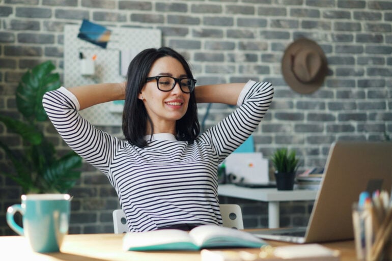 Woman relaxing at a desk in front of a laptop