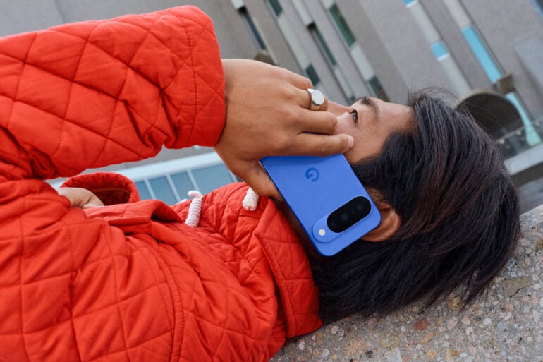 Google Pixel 10 Indigo held by model in bright jacket