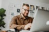 Man smiling while using a laptop