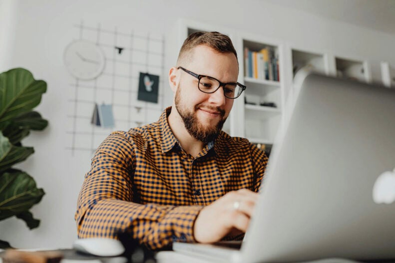 Man smiling while using a laptop