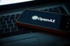 OpenAI logo on a phone sitting on a laptop