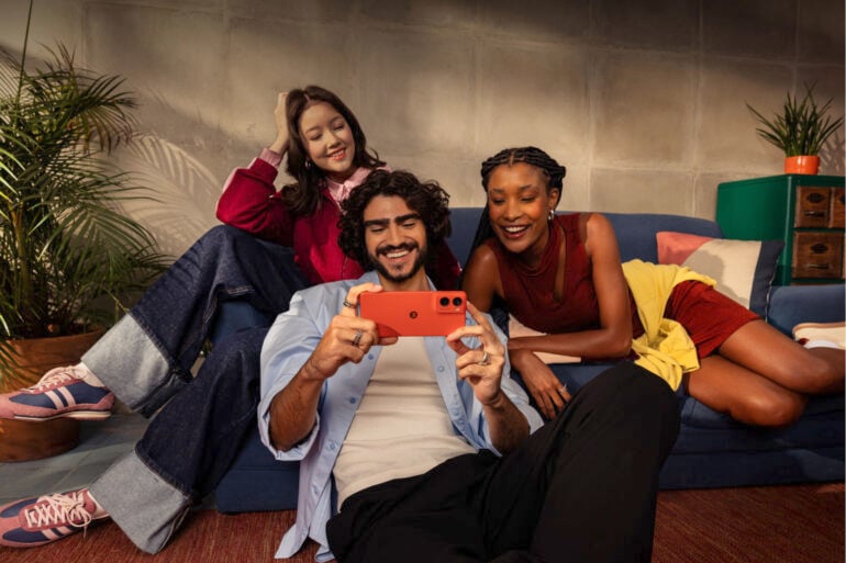 Group of people holding orange Moto G06 phone