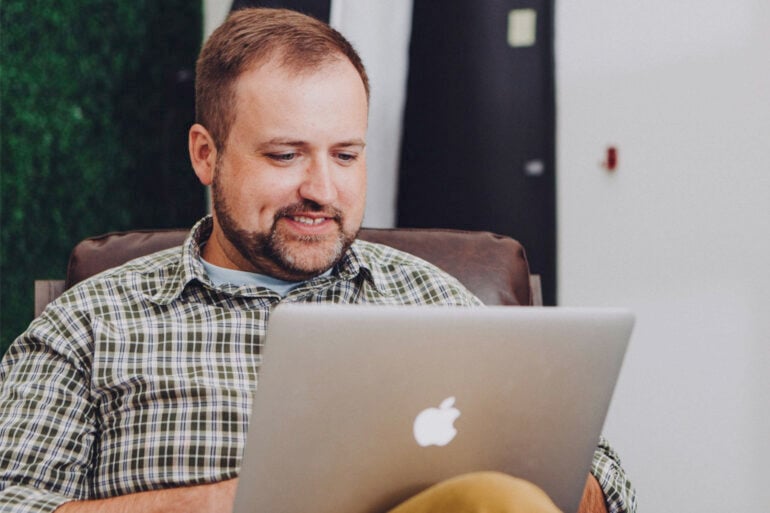 Man smiling at MacBook stock image