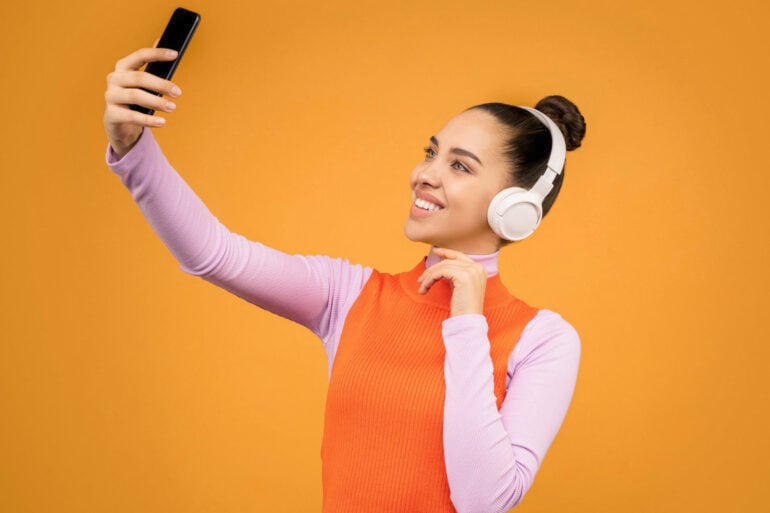 Woman taking selfie orange bg stock image