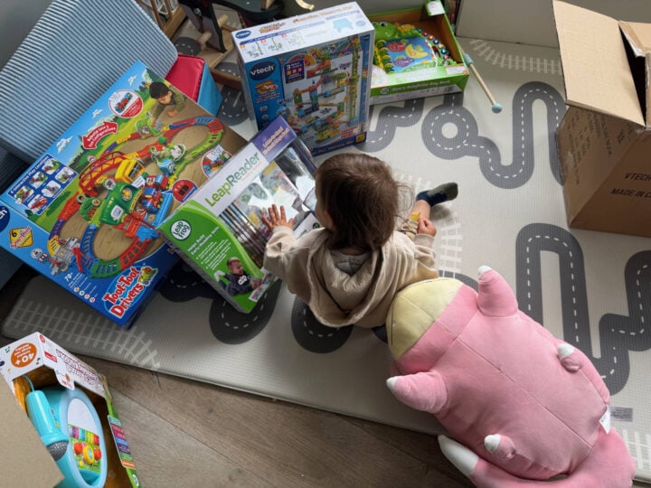 A toddler surrounded by toys and a LeapFrog book