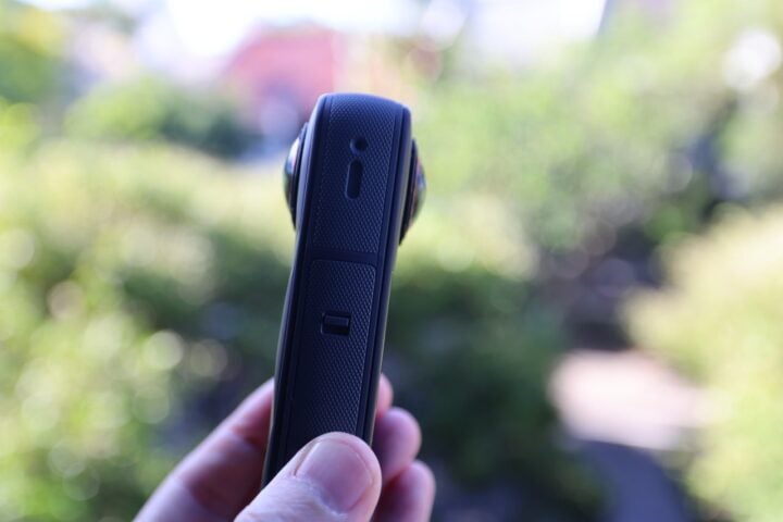 Insta360 X5 hand-held showing twin cameras and trees in the background