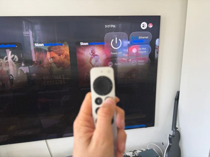 Apple TV remote with TV in background