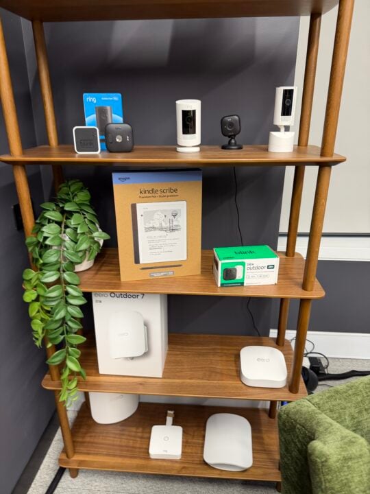 Shelf display of Ring and Blink security cameras, a Kindle Scribe and Eero Wi-Fi routers