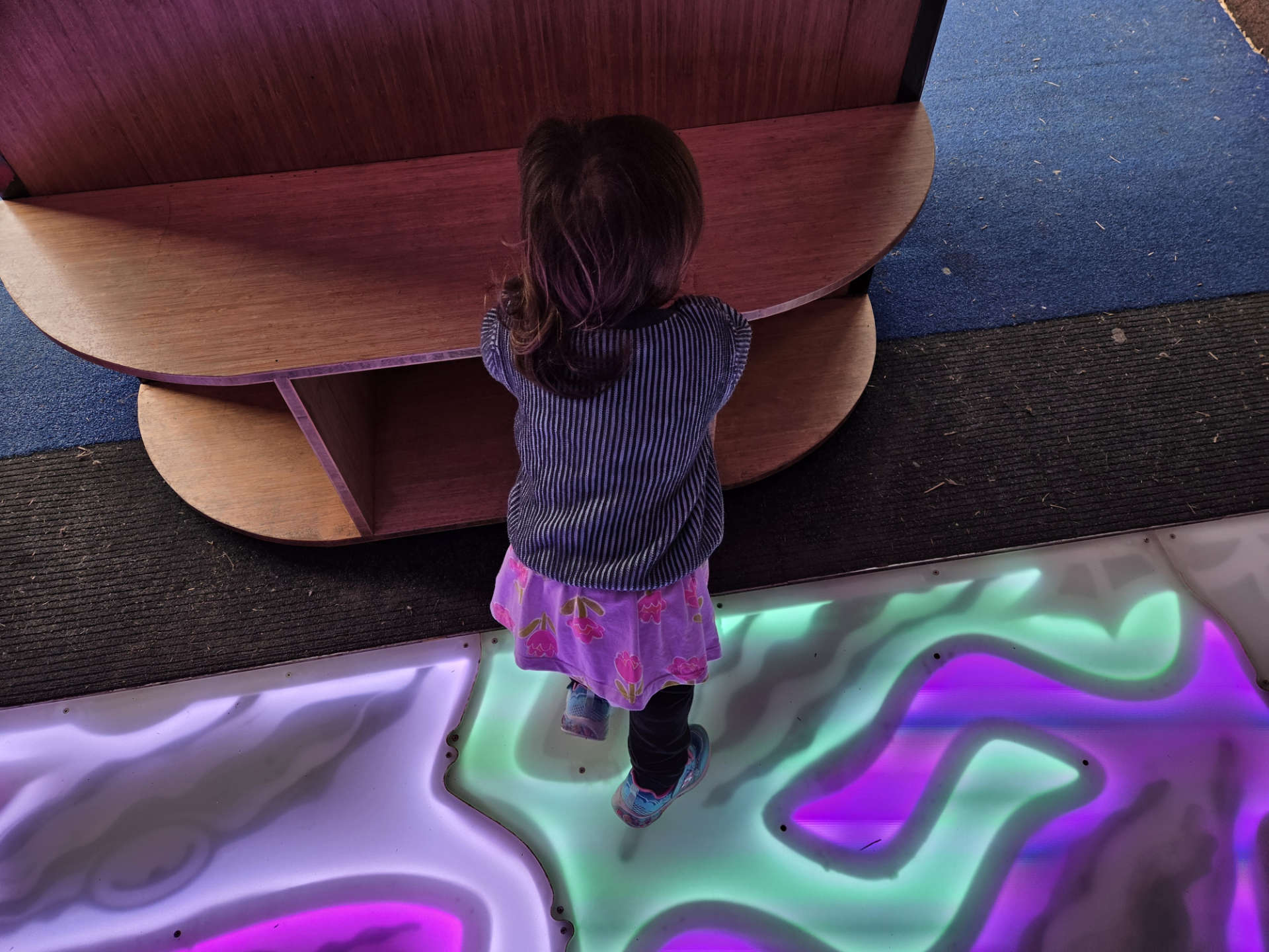 Photo of a young child standing on a colourful floor