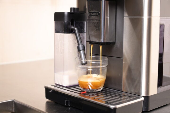 Coffee maker pouring coffee into cup with two spouts.