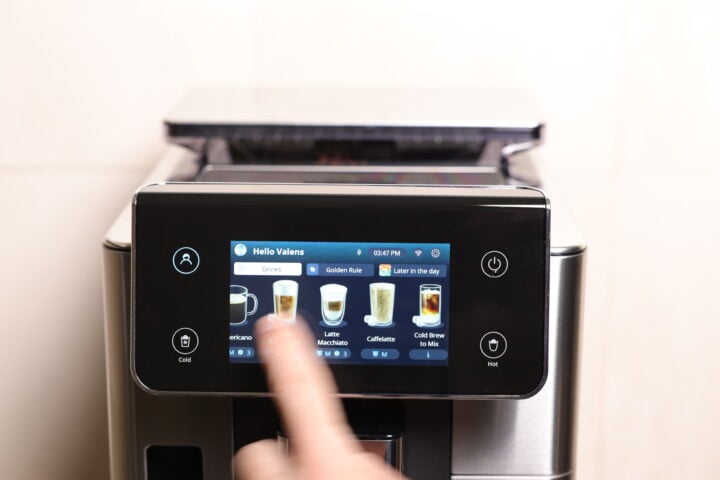 Hand using the 4.3 inch touchscreen display on the De'Longhi PrimaDonna  coffee maker.