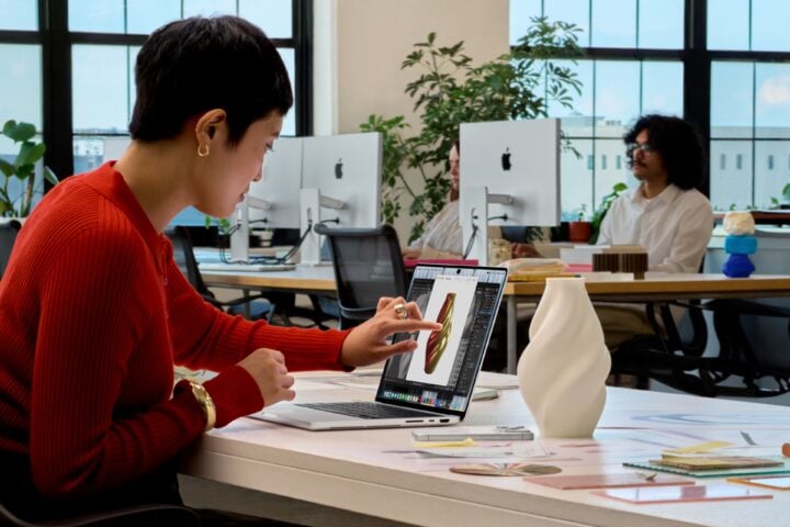 Woman using touch on a MacBook Pro screen to work on a 3D model in an office