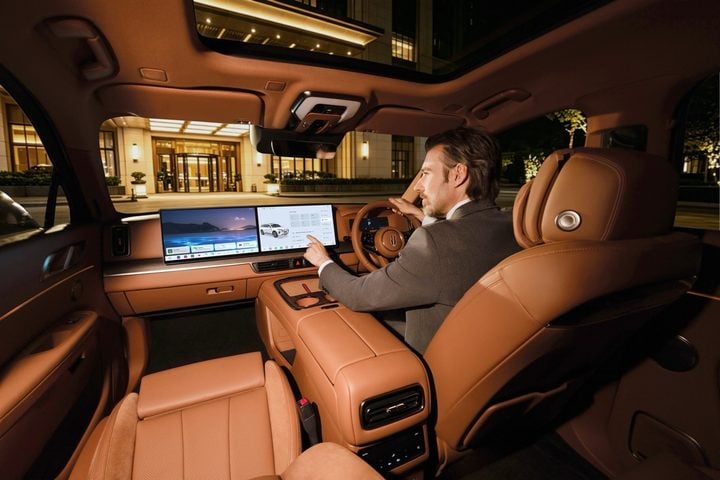 Rear-seat passenger in the HongQi E-HS9’s tan leather cabin, with screens and a panoramic sunroof